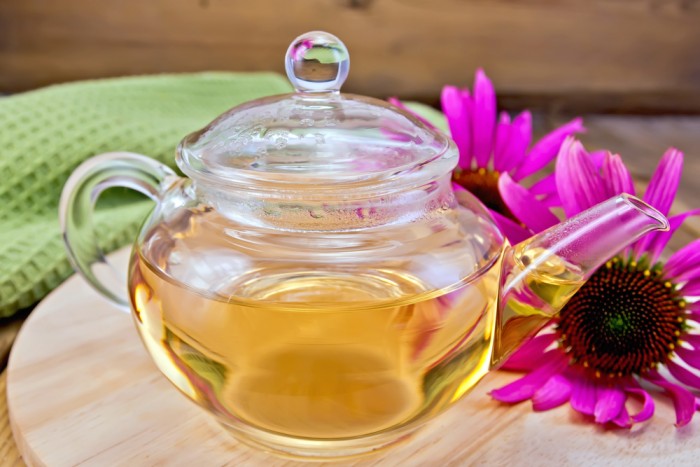 Tea from Echinacea in glass teapot on board with cloth