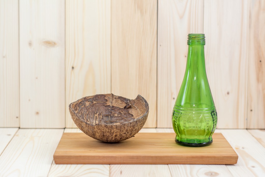 Coconut shell with green glass bottles on splat.
