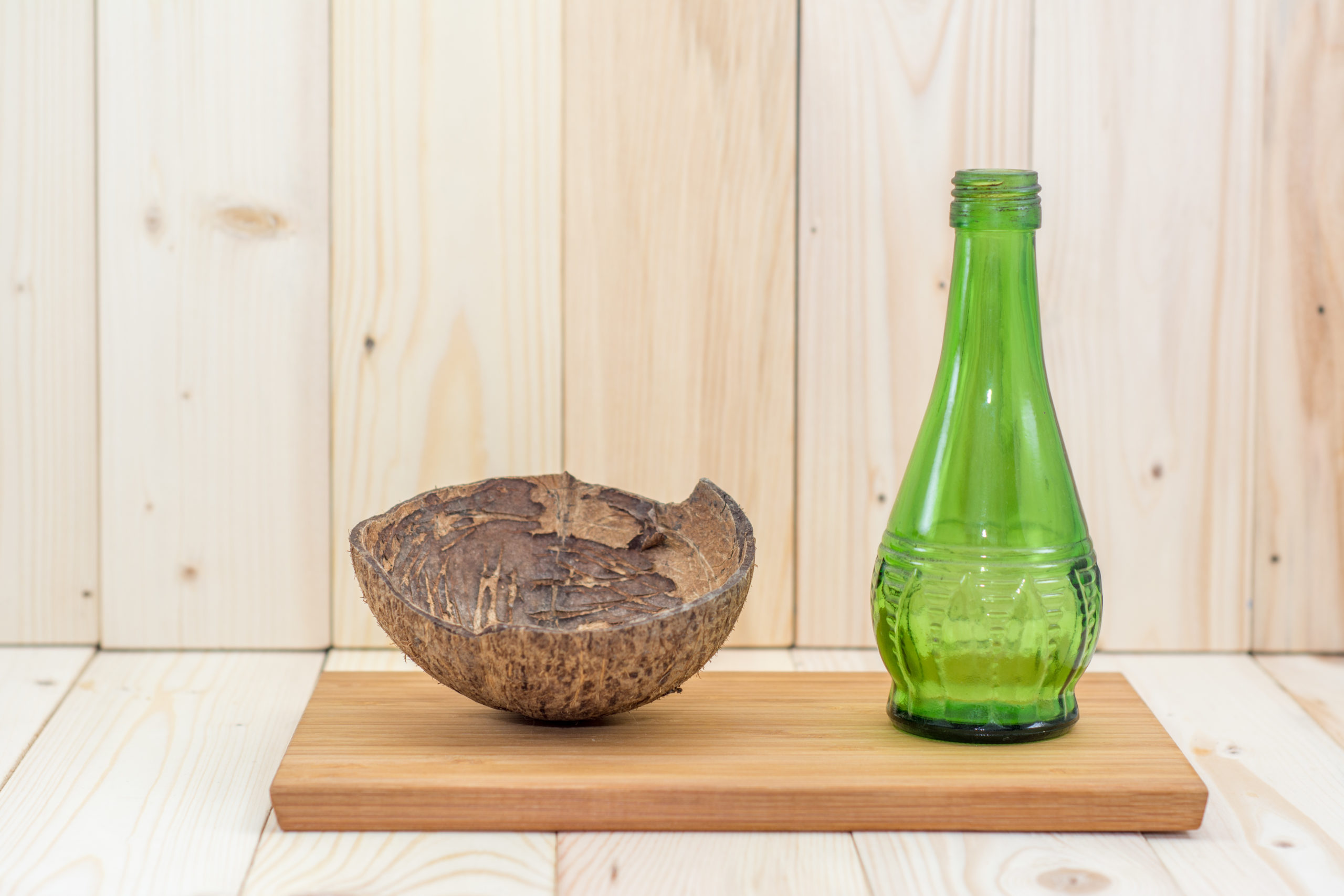 Coconut shell with green glass bottles on splat.