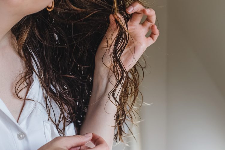Close-up of feminine hand holding a strand of her wavy hair.