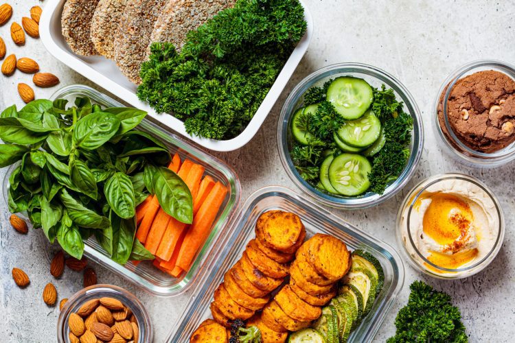 Preparing healthy food for the week, top view. Vegan food and healthy snacks in containers, gray background.