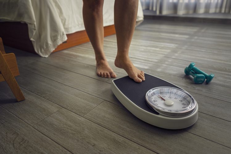 Close up of female leg stepping on weigh scales.Wellbeing weight control and exercising concept